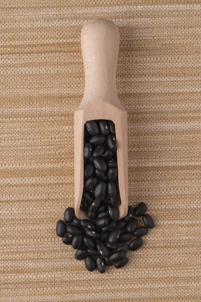 Wooden scoop with black beans — Stock Photo, Image