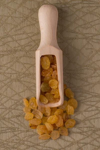Wooden scoop with golden raisins — Stock Photo, Image