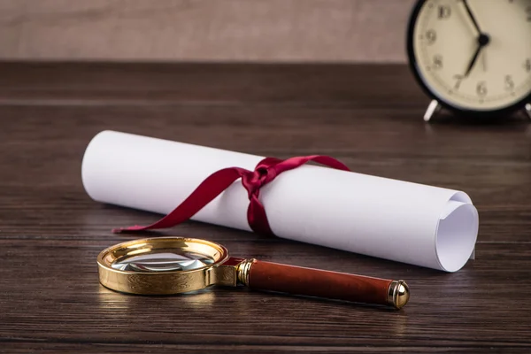 Wrapped paper sheets and magnifying glass — Stock Photo, Image