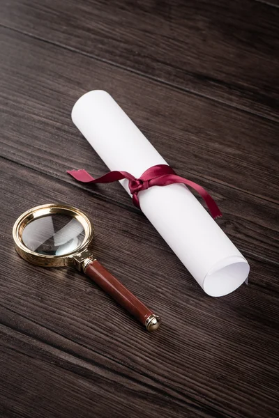 Wrapped paper sheets and magnifying glass — Stock Photo, Image