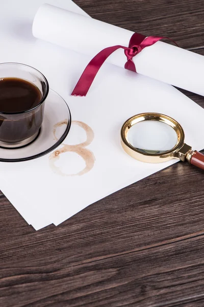 Coffee cup, paper sheets and detective magnifying glass — Stock Photo, Image