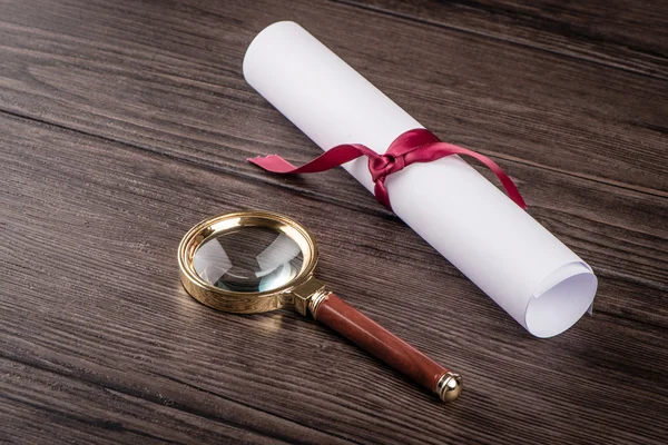 Wrapped paper sheets and magnifying glass — Stock Photo, Image