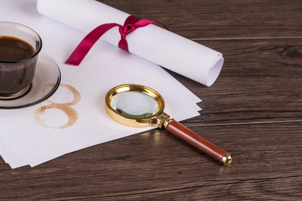 Coffee cup, paper sheets and detective magnifying glass — Stock Photo, Image