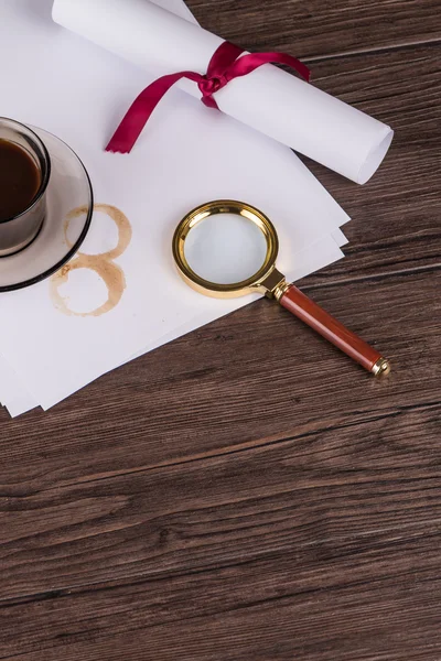 Coffee cup, paper sheets and detective magnifying glass — Stock Photo, Image