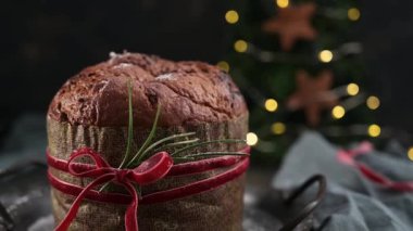 Geleneksel İtalyan Panettone pastasının sıcak, yakın çekim bir hediye olarak sunulmuş ve kırmızı kadife kurdele ve biberiye filizi ile bağlanmış..