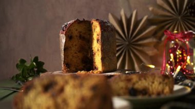 Geleneksel İtalyan panettonunun karanlık, yatay, durgun bir hayatı. Meyve ve ve çikolatayla süslenmiş zengin, altın rengi iç kısımları göstermek için kısmen dilimlenmiş..