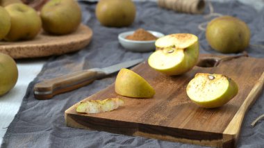 Yarısı kesilmiş bir elma ve bir kama tarçın serpiştirilir ve kırsal bir ahşap kesme tahtasının üzerinde dinlenir. Sahne bir bıçak, sicim ve küçük bir kase tarçınla ayarlanmış. Bu da samimi ve sonbahar hazırlıklarını gösteriyor..