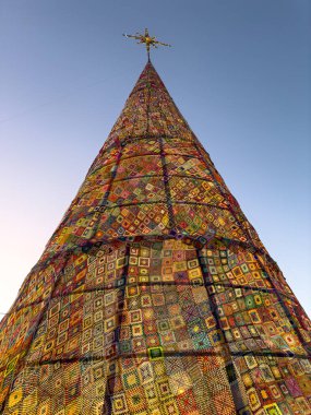 Aşırı düşük açılı bir çekim, Portekiz 'in Ovar kentindeki muazzam yüksekliği ve koni şeklini vurguluyor ve bu ağaç karmaşık, canlı bir örgü ve örgü yamasıyla kaplanıyor. El yapımı tekstil dokusu son derece görünür, inte ile aydınlatılır.