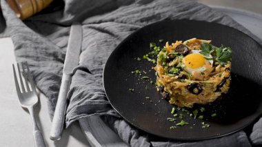 Geleneksel Portekiz morina balığının sofistike bir sunumunda bıldırcın yumurtası ile kaplanmış dokulu dairesel bir küf bulunur. Yumuşak kenar ışıklandırması kırsal çarşafları vurgular.