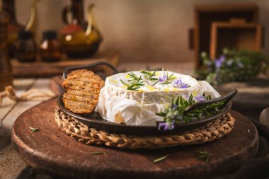 Taze biberiye ve zeytinyağıyla kaplanmış erimiş Camembert peynirinden oluşan sıcak bir tekerlek. Kırsal ahşap bir tahtanın üzerinde kızarmış baget dilimleri ile servis ediliyor..