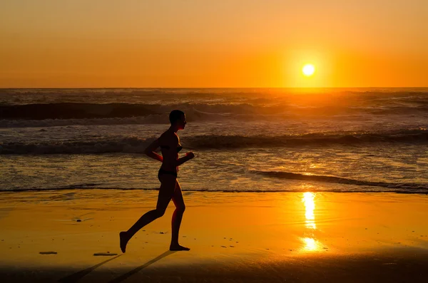 Femme jogger courir sur la plage du coucher du soleil — Photo
