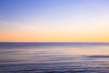 Gün batımında kumsaldan okyanus, renkli gökyüzü ve deniz manzarası