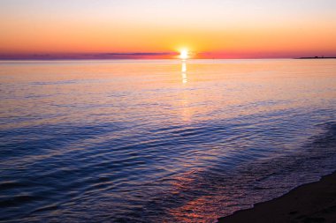 Gün batımında kumsaldan okyanus, renkli gökyüzü ve deniz manzarası