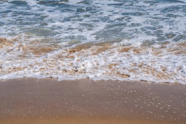 Okyanus doğası, kıyıya vuran dalgalar gibi köpüklü suyun yakın plan detaylarının görüntüsü. 