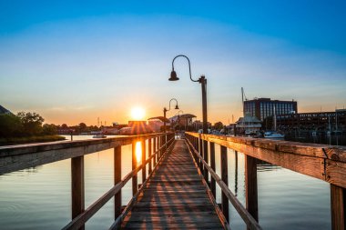 Hampton Virginia şehir merkezi rıhtım bölgesi gün batımında renkli gökyüzünün altında görülüyor.