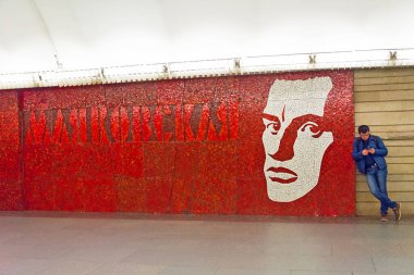 ST. PETERSBURG, RUSSIA - MAY 31, 2017: People move past the portrait of the famous poet Mayakovsky, Mayakovskaya metro station, St. Petersburg, Russia clipart