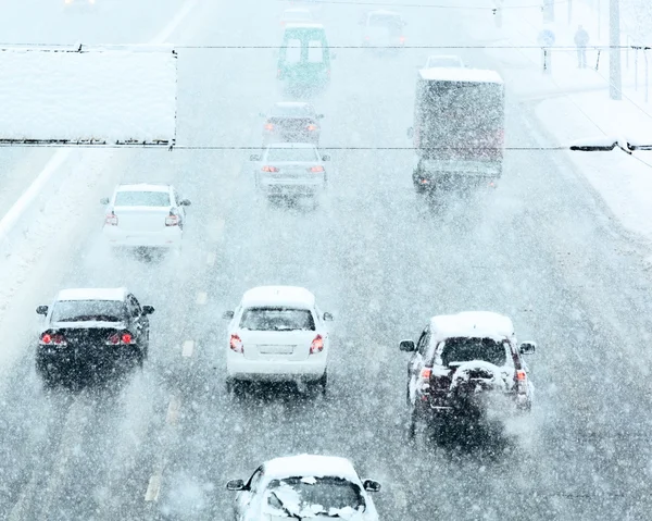 Route d'hiver enneigée avec des voitures conduisant sur la chaussée dans la tempête de neige — Photo