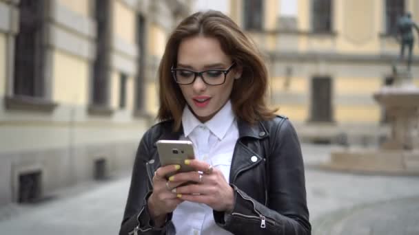 Дівчина йде по вулиці зі своїм телефоном — стокове відео