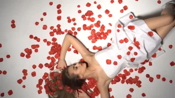Красивая женщина улыбается с падающими лепестками роз — стоковое видео