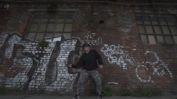 Активная девушка танцует на кирпичной стене на фоне ярлыков . — стоковое видео