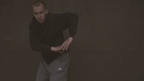 Active young male dancing on a black metal door and brick wall background in slow motion. — Stock Video