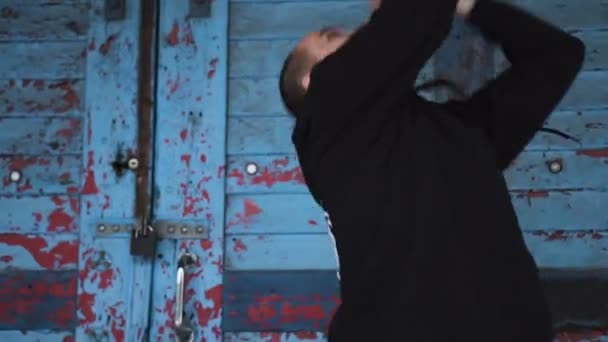 Active młody mężczyzna tańczy na stare niebieskie drzwi i cegły tle ściany. — Wideo stockowe