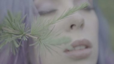 Kozalaklı ormanda mor saçlı güzel kadın Closeup - peri masalı sahne. Video şehvetli güzellik, ağaca dokunmadan dal ve yavaş hareket yüzünü ve saçları.