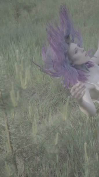 Belle femme aux cheveux violets tombant sur le sol dans la forêt scène de conte de fées. Vidéo de beauté sensuelle sur herbe verte au ralenti . — Video