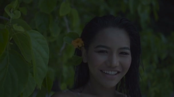 Asiatische schöne glückliche Frau im gehäkelten Bikini, die am Strand spazieren geht. Video von sexy lächelndem Mädchen am Strand mit der Blume im Haar in Zeitlupe. — Stockvideo