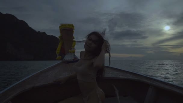 Asian beautiful sensual woman in crochet bikini on the boat. Video of sexy girl sitting on the drifting boat with wind in her hair and looking into the camera - front view in slow motion. — Stock Video