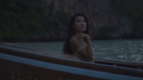 亚洲性感美女在钩针比基尼在船上。性感的女孩坐在小船上，望着天空中慢动作的视频. — 图库视频影像