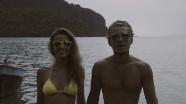 Güzel genç mutlu çift el ele tutuşarak ve yavaş hareket deniz ve dağların güzel görünümü ile tatil sırasında iskele yürüyüş.