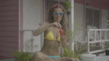 Pembe evin arka planında izole sabun kabarcıkları yapıyor bikini ve güneş gözlüğü giyen Pretty genç kadın.