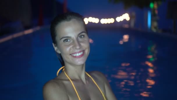 Femme heureuse se détendre à la piscine de luxe dans la soirée. Vidéo 4k de femme à la piscine . — Video