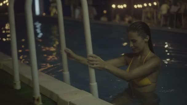 Sexy mladá žena drží ruku kolejnice a šla z bazénu. — Stock video
