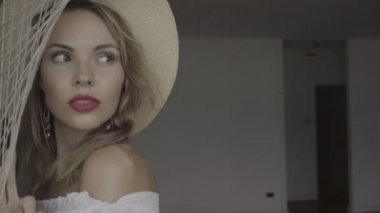 Boho tarzı moda yaz gününde Pretty doğal görünümlü kadın beyaz gömlek, bikini ve şapka terk edilmiş bir binada yürüyüş ve güzel yeşil yaprakları arka plan üzerinde pencereden bakarak giyiyor.