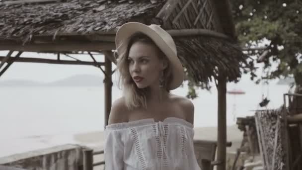 Mujer de aspecto bastante natural en estilo boho con camisa blanca, bikini y sombrero en un hermoso día de verano - video en cámara lenta . — Vídeos de Stock