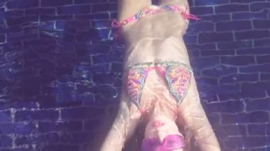Güneşli bir günde - ağır çekimde video yüzme havuzunda yalan bikini ve mor güneş gözlüğü takıyor seksi genç kadının Üstten Görünüm.