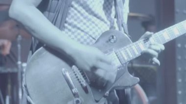 Değişen renklersahne ışıkları ile canlı performans sırasında gitar çalan bir adamın yakın çekim.