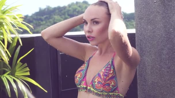 Widok z przodu seksowna blondynka w bikini biorąc prysznic na zewnątrz na dachu otoczony tropikalnym ogrodem - slow motion video. — Wideo stockowe