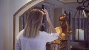 Glamour güzel kadın lüks daire aynada yüzünü kontrol gömlek ve mavi kot şort giyiyor.