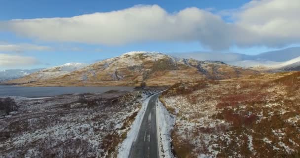 Aéreo: Vista deslumbrante da estrada perto do lago em Highlands no inverno, Norte da Escócia — Vídeo de Stock