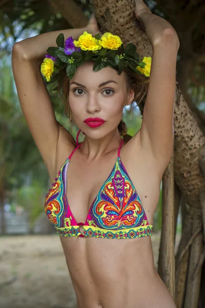 Closeup of beautiful blonde glamour woman wearing colourful swimwear and wreath posing on a beautiful summer day between palm trees — Stock Photo, Image