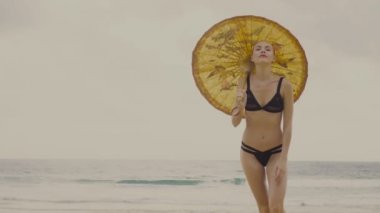 Güzel sarışın glamour kadın çin şemsiyesi gülümseyerek siyah mayo giyen ve plajda güzel bir yaz gününde poz