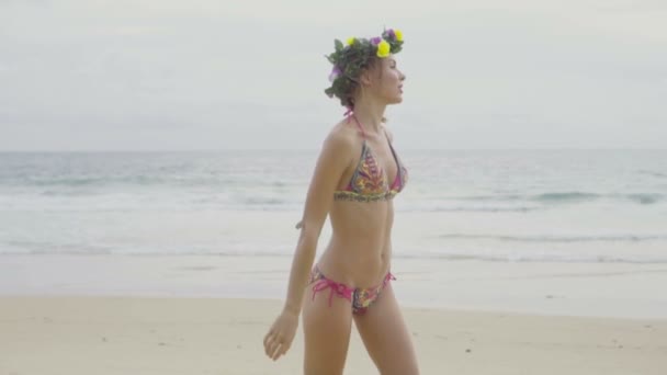 Renkli mayo ve çelenk giyen güzel sarışın mutlu kadın gülümseyerek ve deniz ve gökyüzü arka plan üzerinde plajda güzel bir yaz gününde poz - yavaş hareket video — Stok video