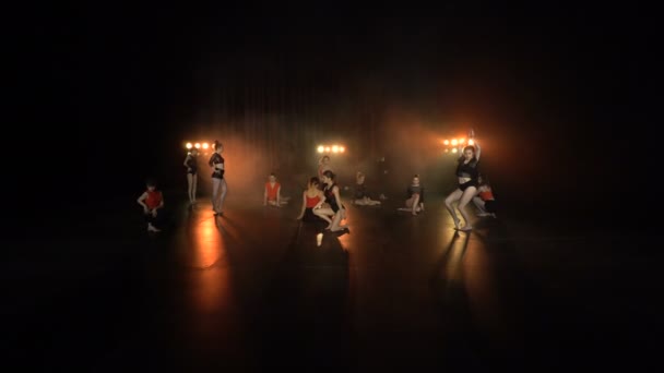 Turuncu ışıklar ve duman ile karanlık bir sahnede seksi kadın grubun Dans performansı — Stok video