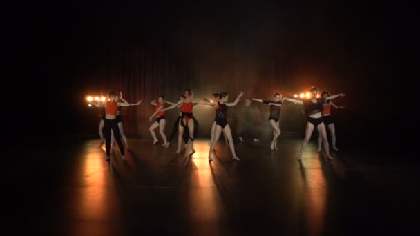 Actuación de baile de grupo femenino sexy en un escenario oscuro con luces naranjas y humo — Vídeo de stock