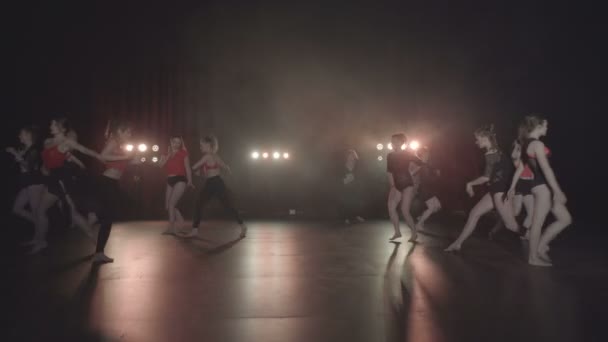 Actuación de baile de grupo femenino sexy en un escenario oscuro con luces naranjas y humo — Vídeo de stock