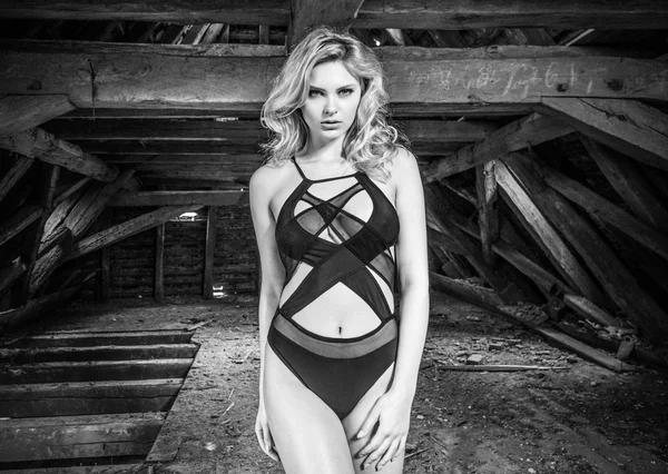 Mulher sensual loira posando no velho sótão de madeira do prédio abandonado vestindo lingerie sexy preta fotografia preto e branco — Fotografia de Stock
