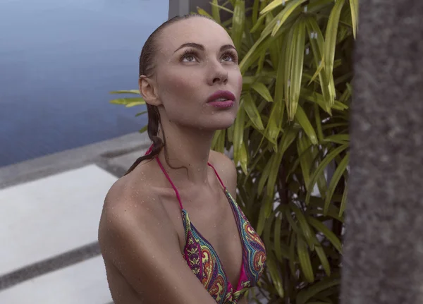 Faccia da vicino della donna bionda sexy in bikini che si fa la doccia all'aperto in piscina circondata da giardino tropicale — Foto Stock